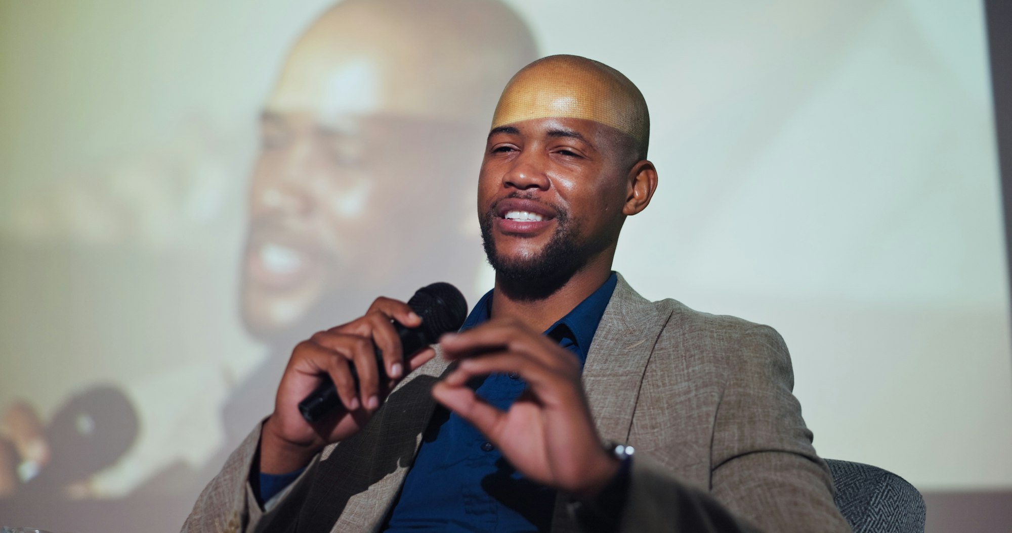 Motivation, speaker and black man at seminar with microphone, screen and presentation of business i