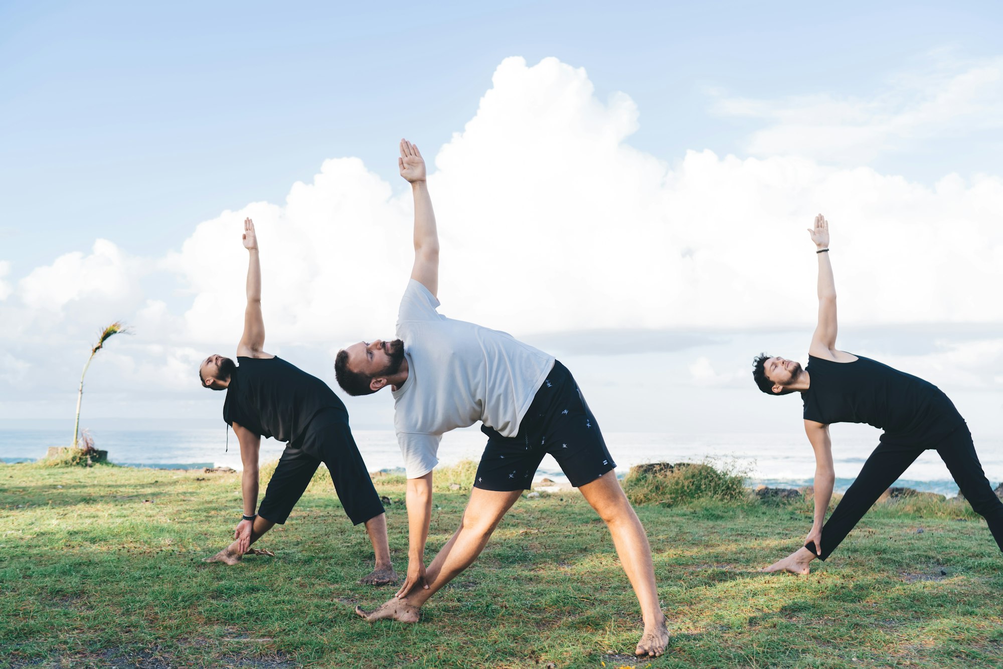 Young flexible men training togetherness during daytime for holistic retreat healing