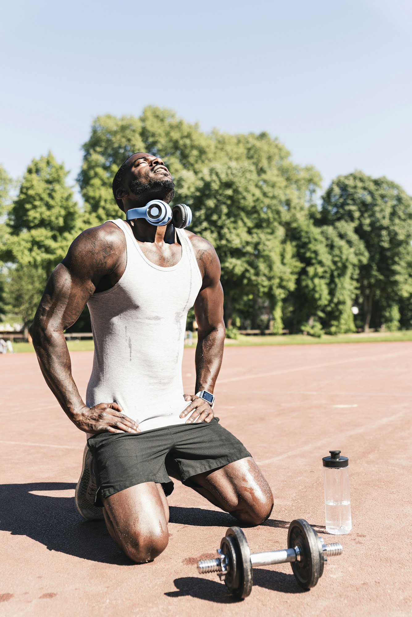 Young athlete doing weight training with dumbbells on sports field